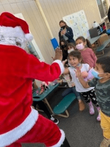 A group of children standing around and playing with santa.