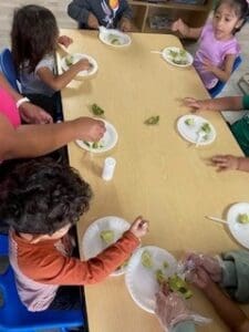 A group of children eating food at the table.