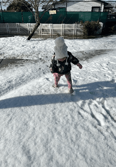 A child in the snow with a stick